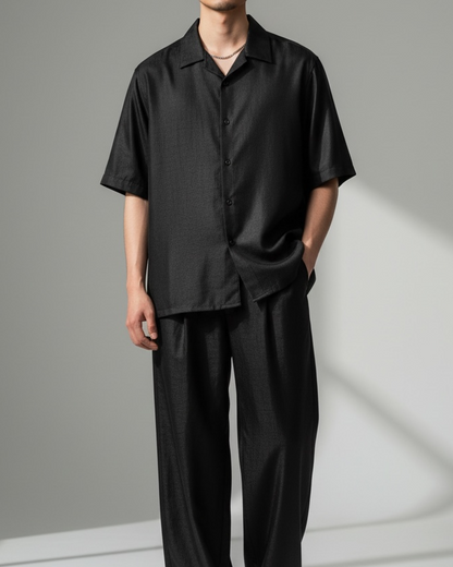 Person wearing a black outfit against a gray background